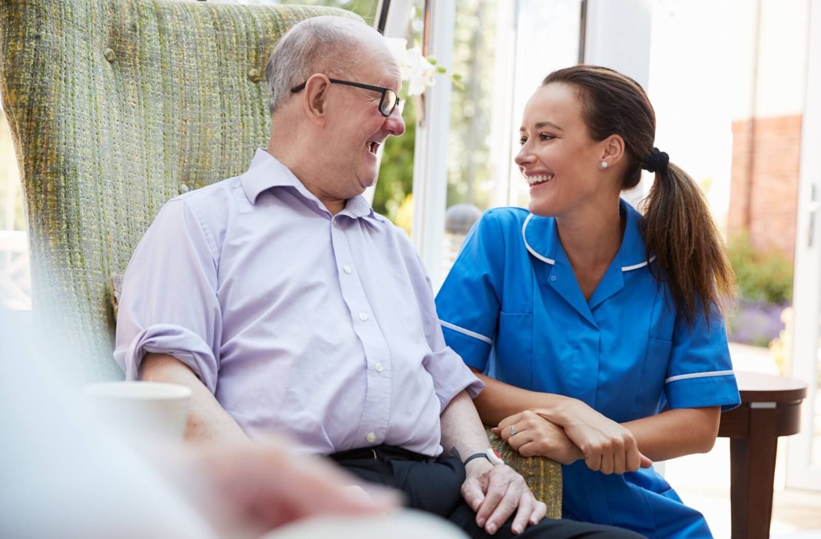 An senior man at a memory care community having a conversation with a care giver.