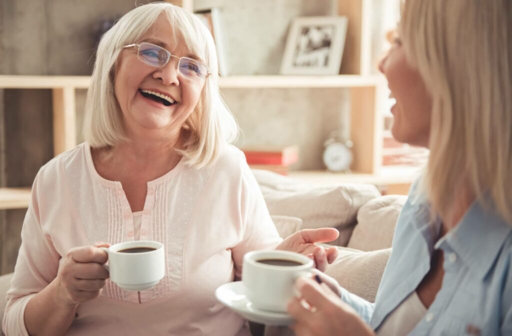 An older woman and her adult daughter share a cup of coffee and a warm conversation with each other.