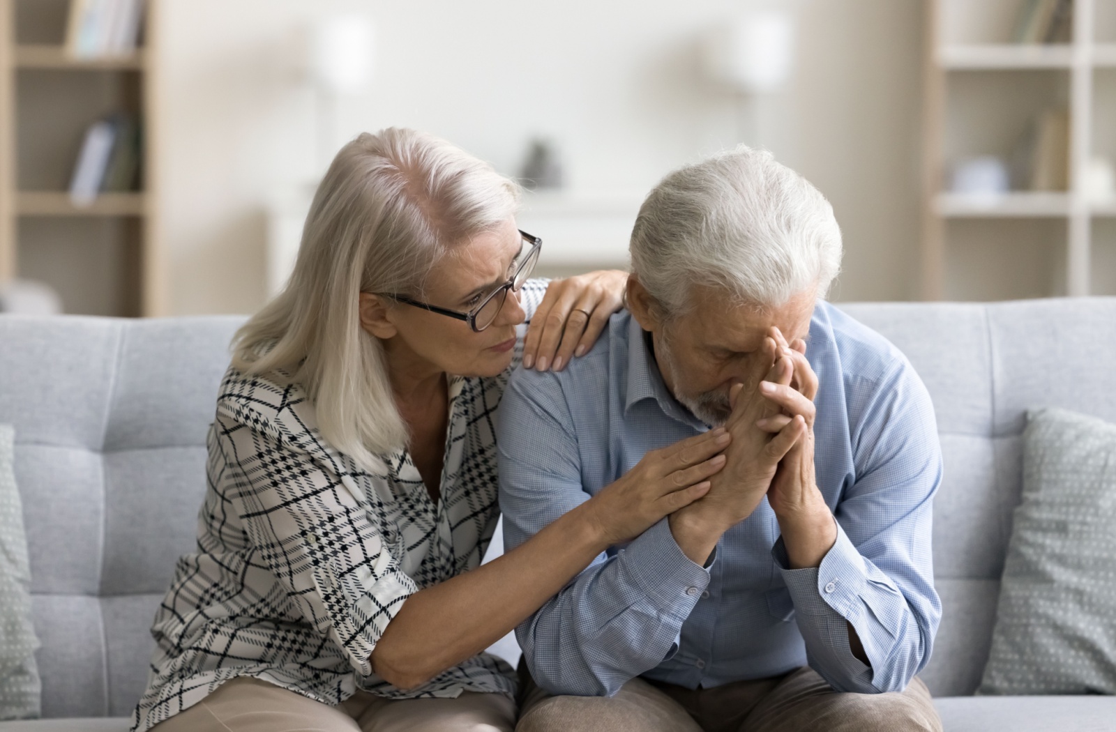 An empathetic wife consoles her husband on their living room couch as he grapples with his memory problems.