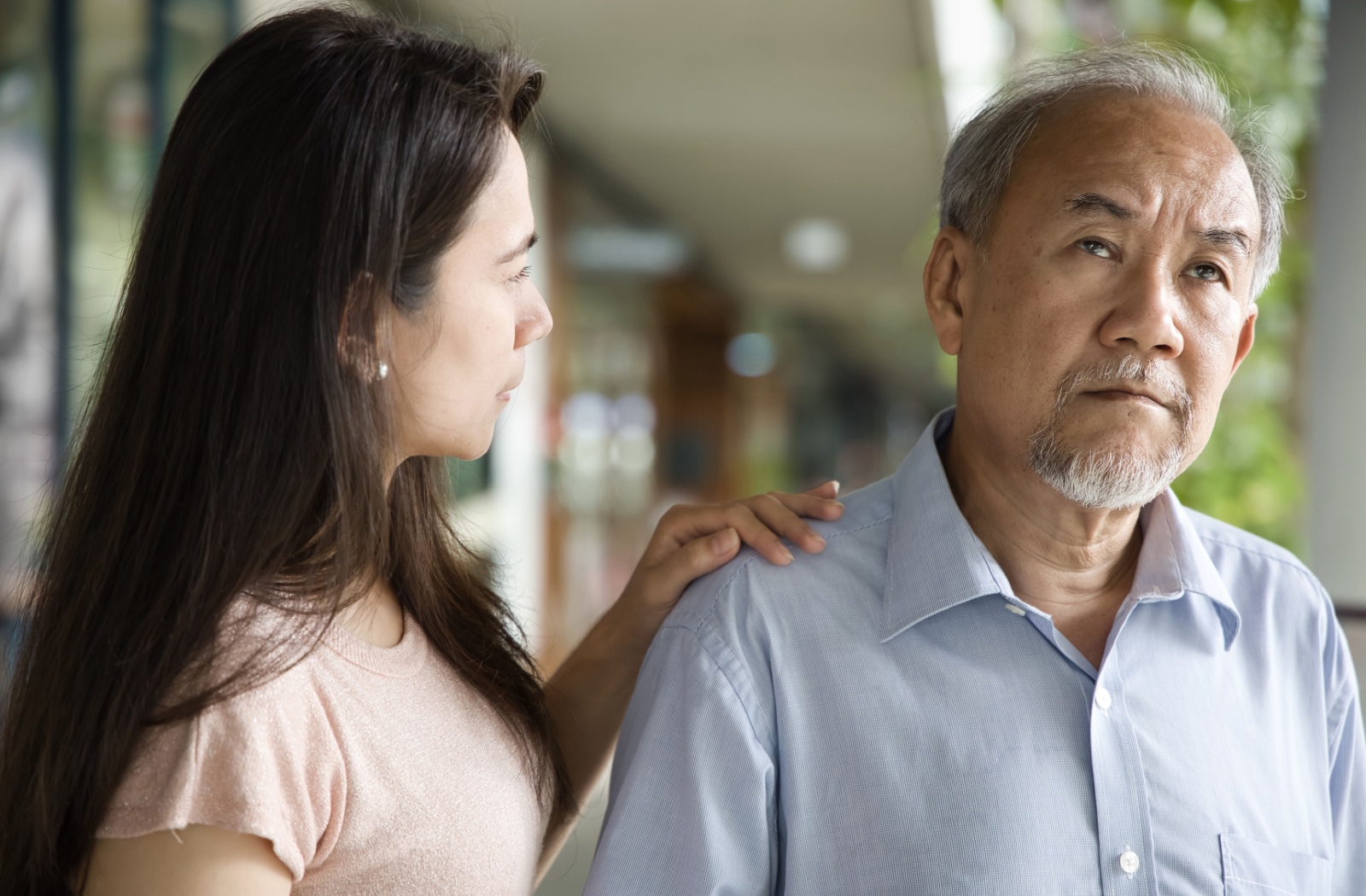 Young woman gently comforting an elderly man with dementia, showing empathy and emotional support during a difficult moment.