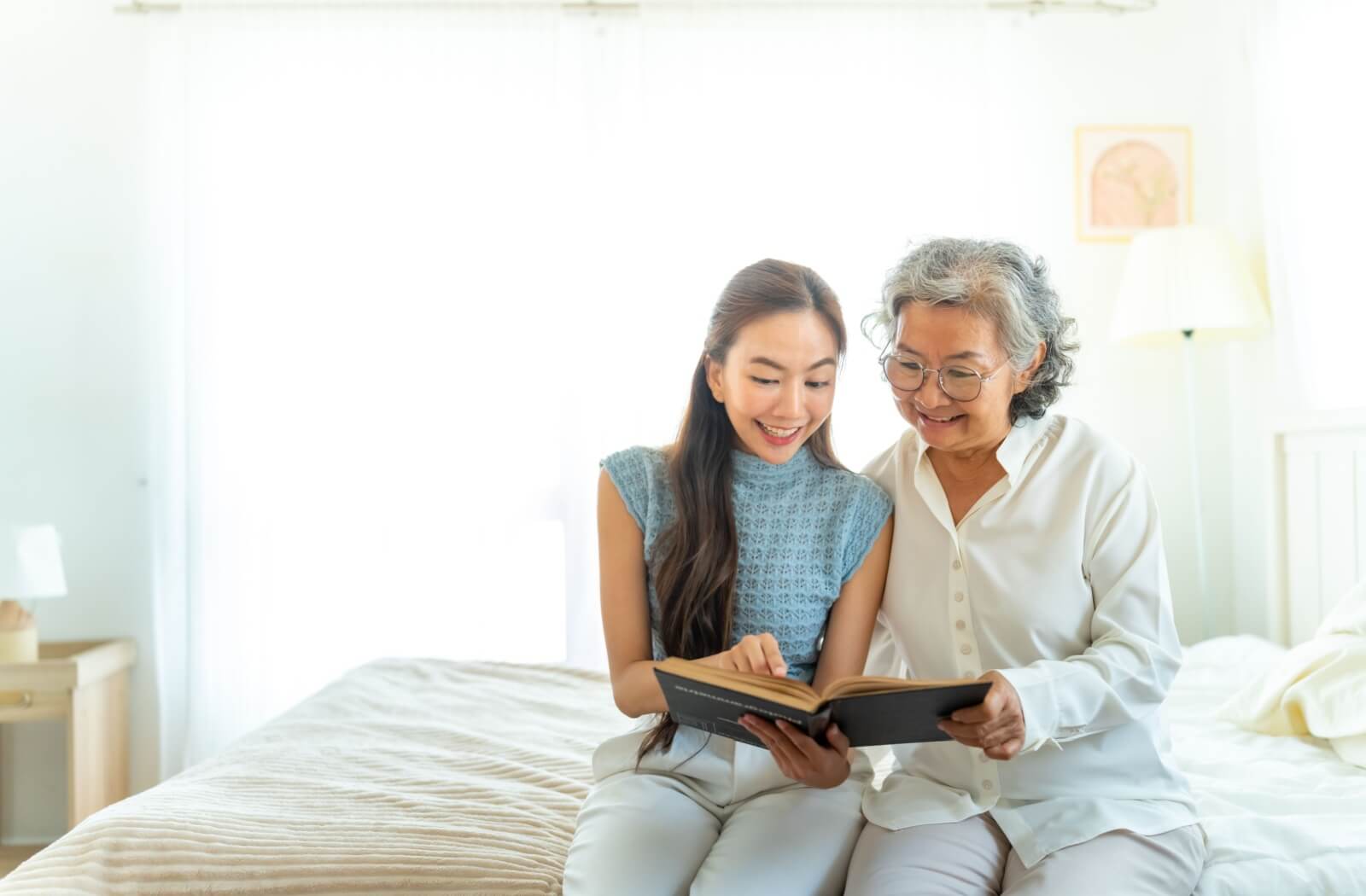 An adult child encouraging their senior parent to read, sharing a supportive and engaging moment together.