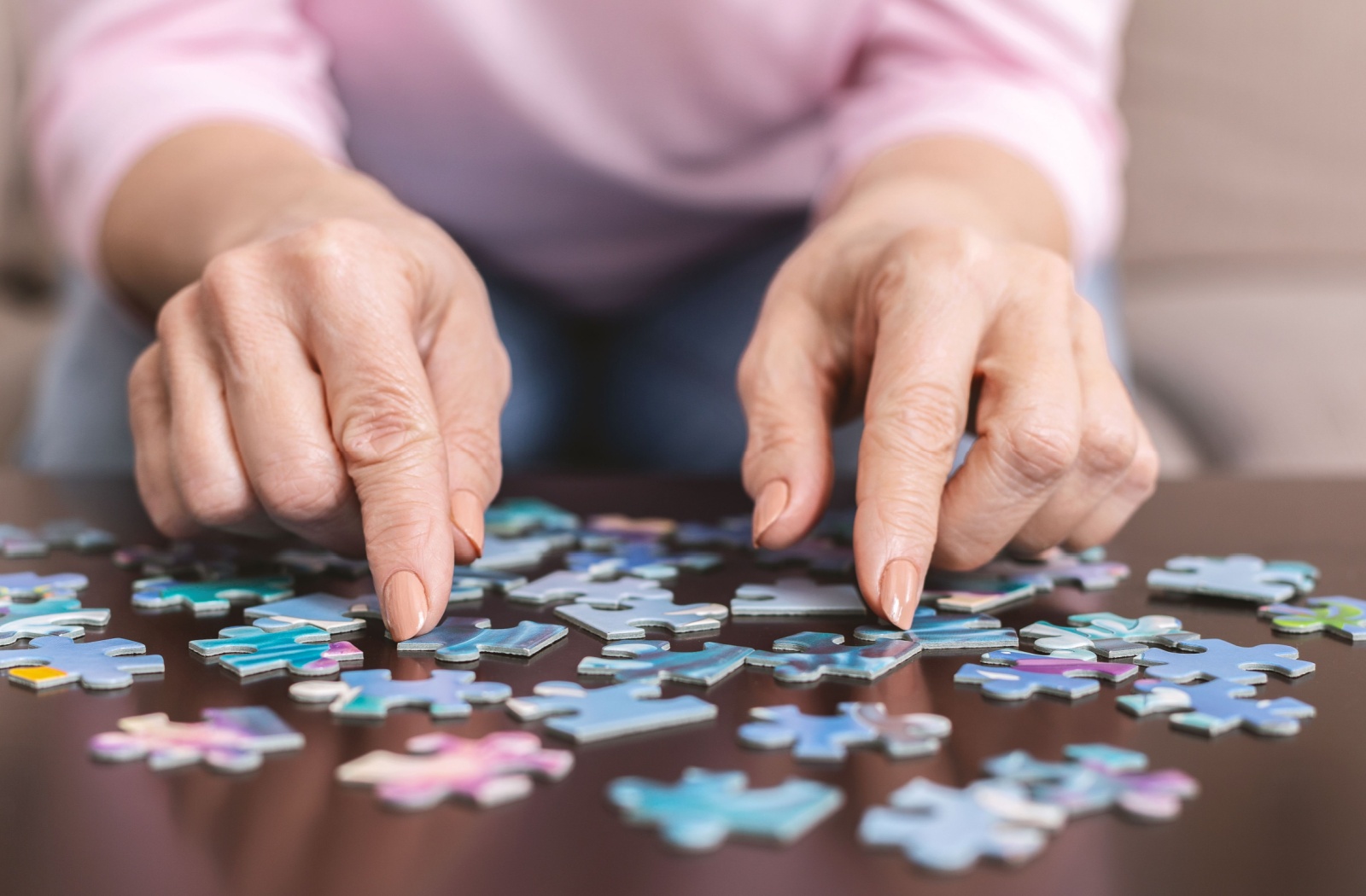 A close-up image of an older adult's hands while they assemble a jigsaw puzzle in memory care.