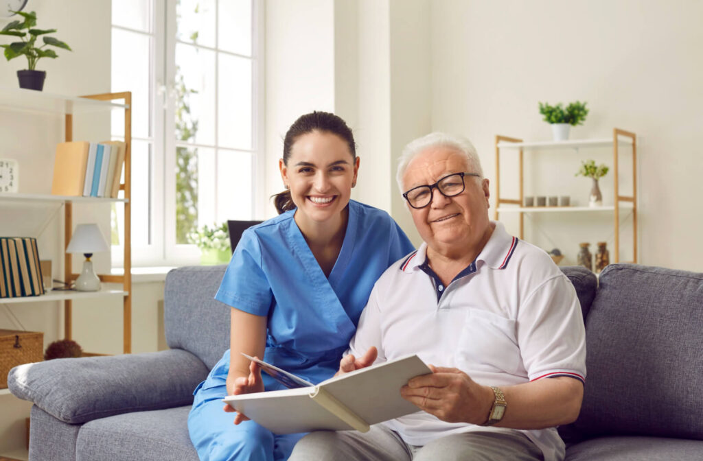 An older adult in memory care smiling while showing a caregiver pictures in a photo album.