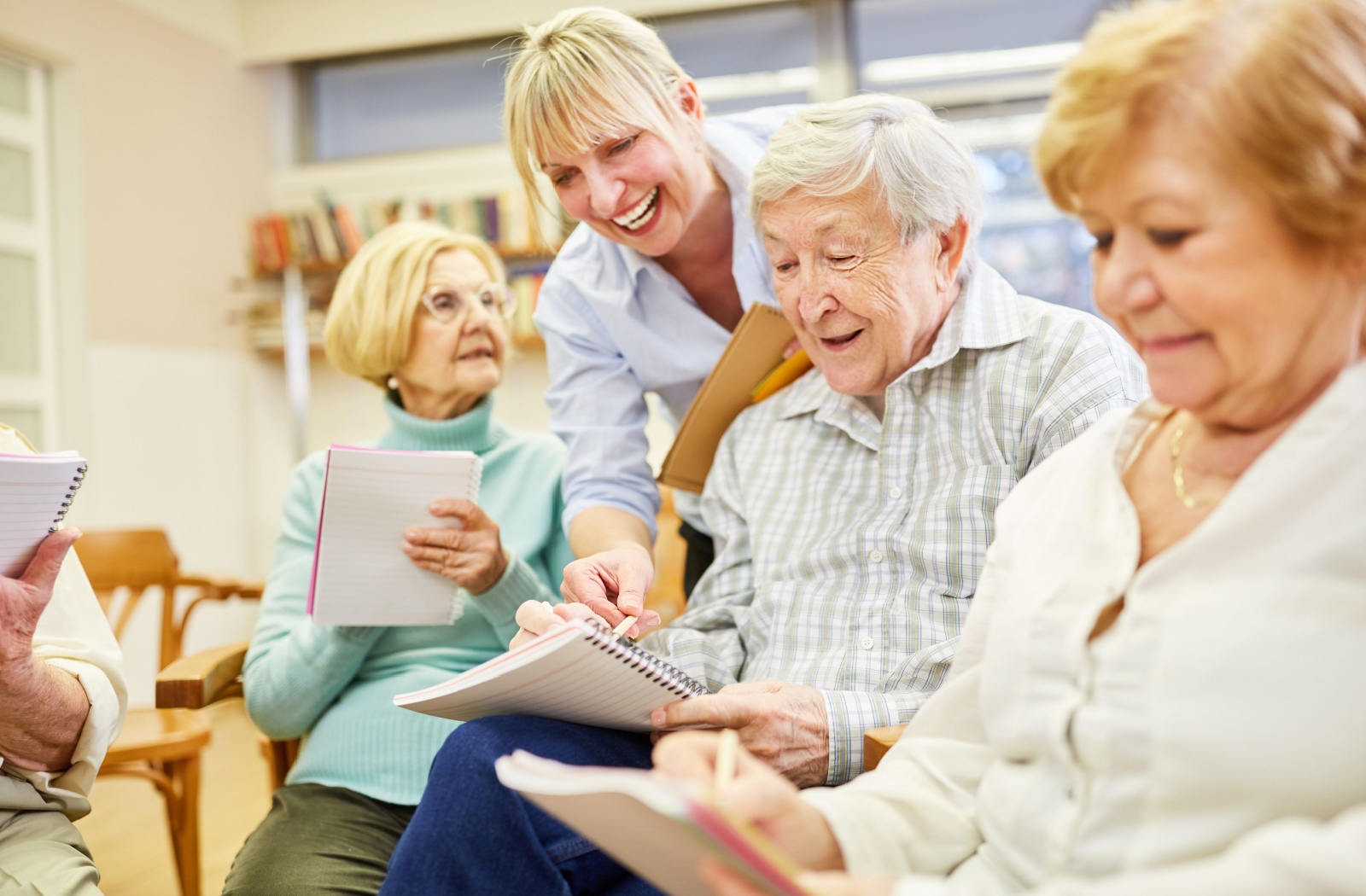 A therapist leads a group of seniors with dementia through sketching art exercises as part of art therapy in memory care