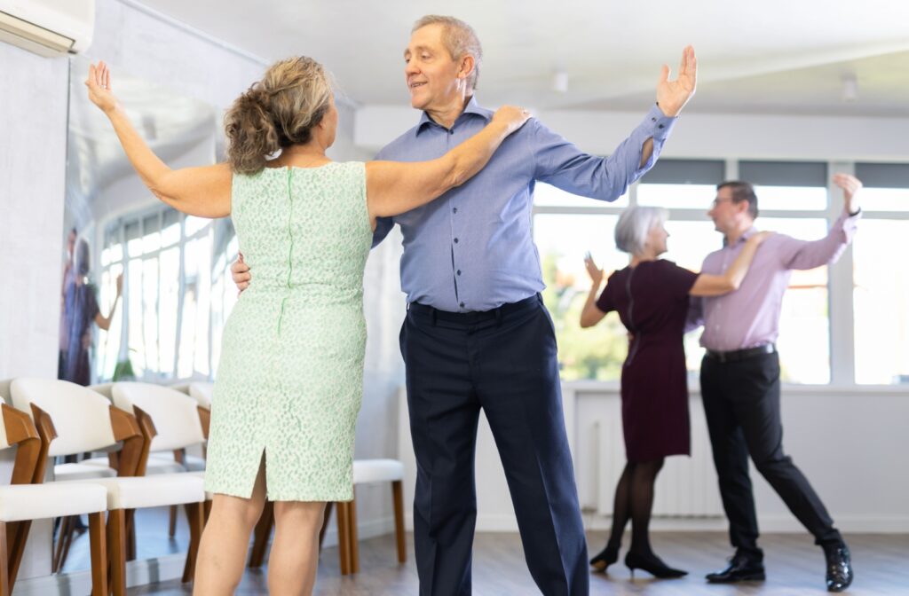 Two senior couples practice dance moves they’ve been taught in a dance class offered by their senior living home