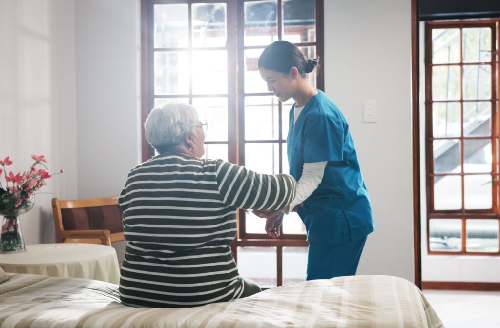 caregiver helping a senior to get up from bed